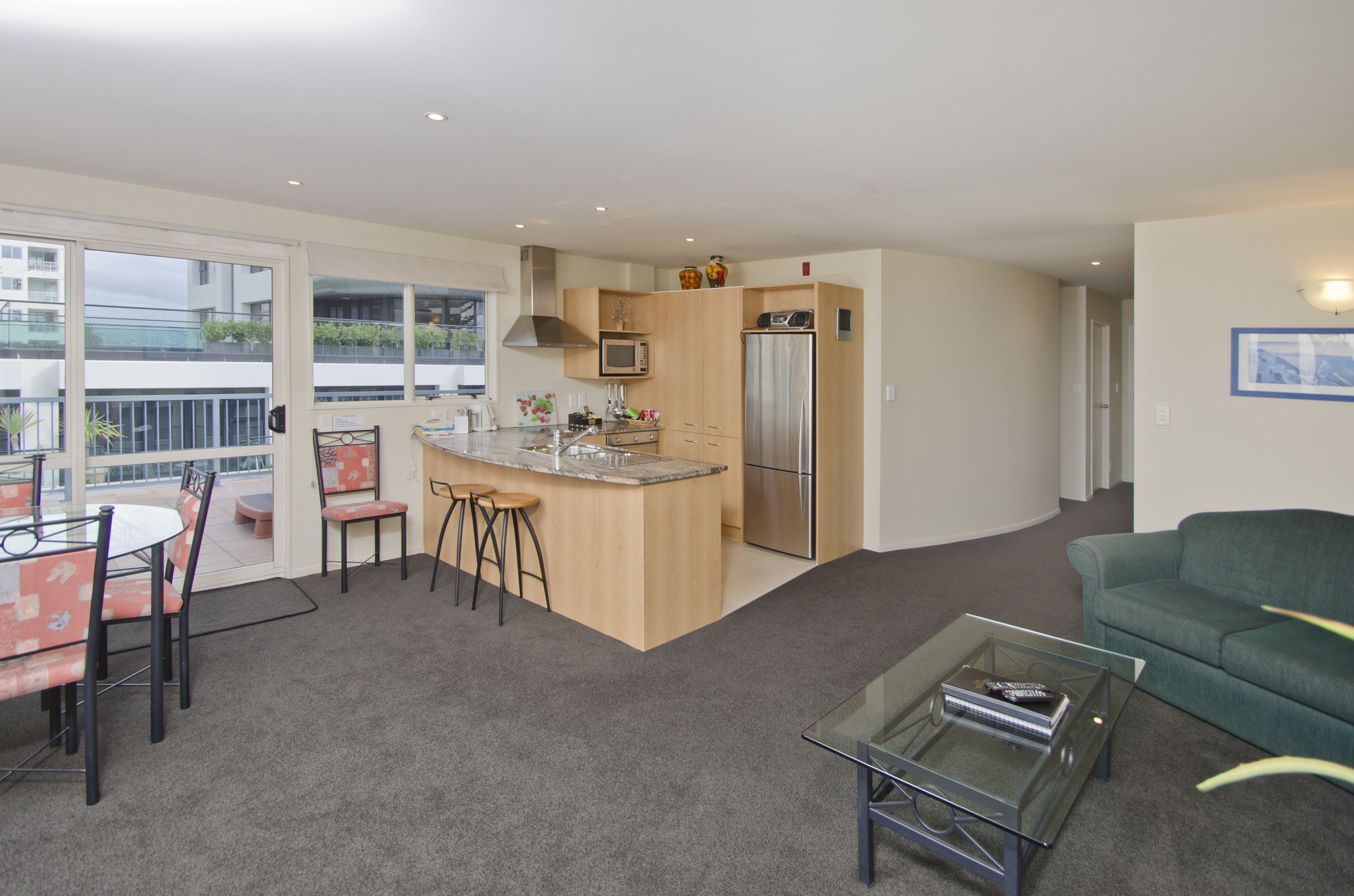 A modern kitchen with a central island, a dining area with a table and chairs, and a green sofa in a living area.