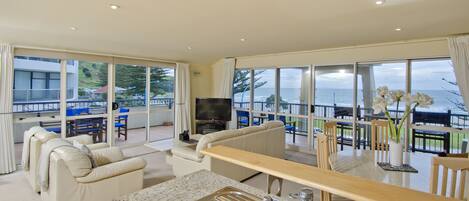 A spacious living area with a kitchen, large windows, and a view of the sea.