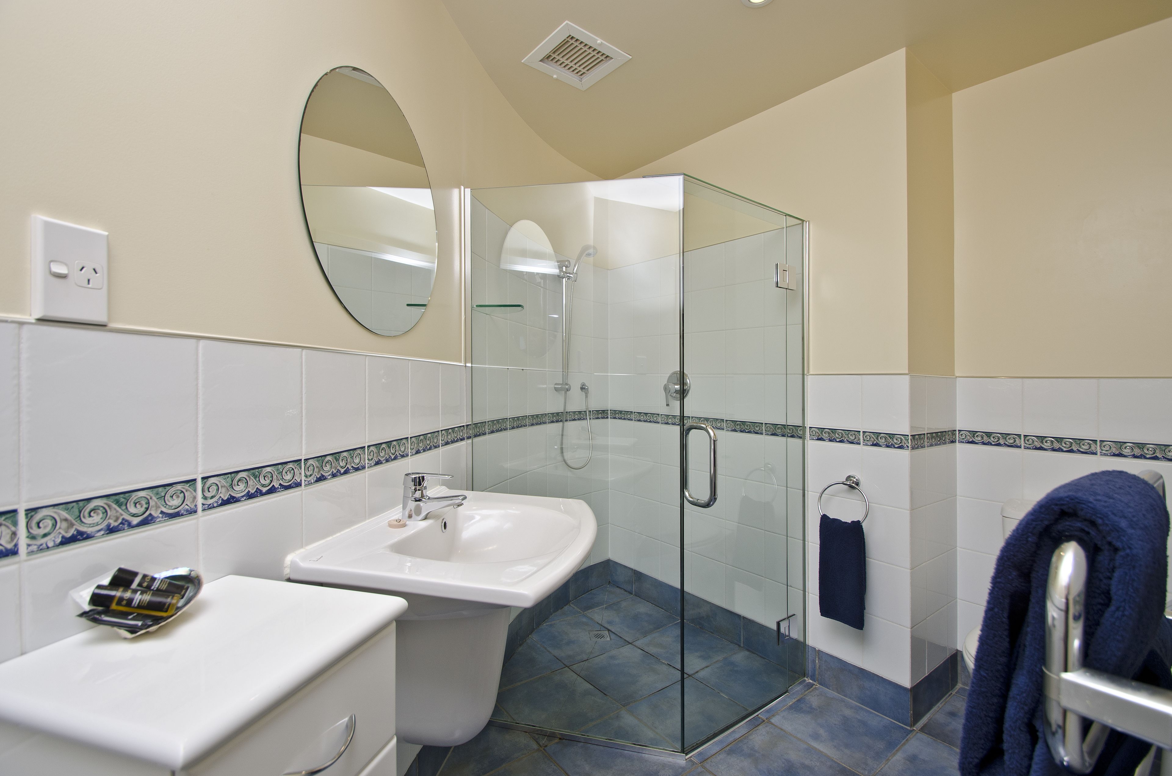 A bathroom with a sink, mirror, shower, and towel rack.