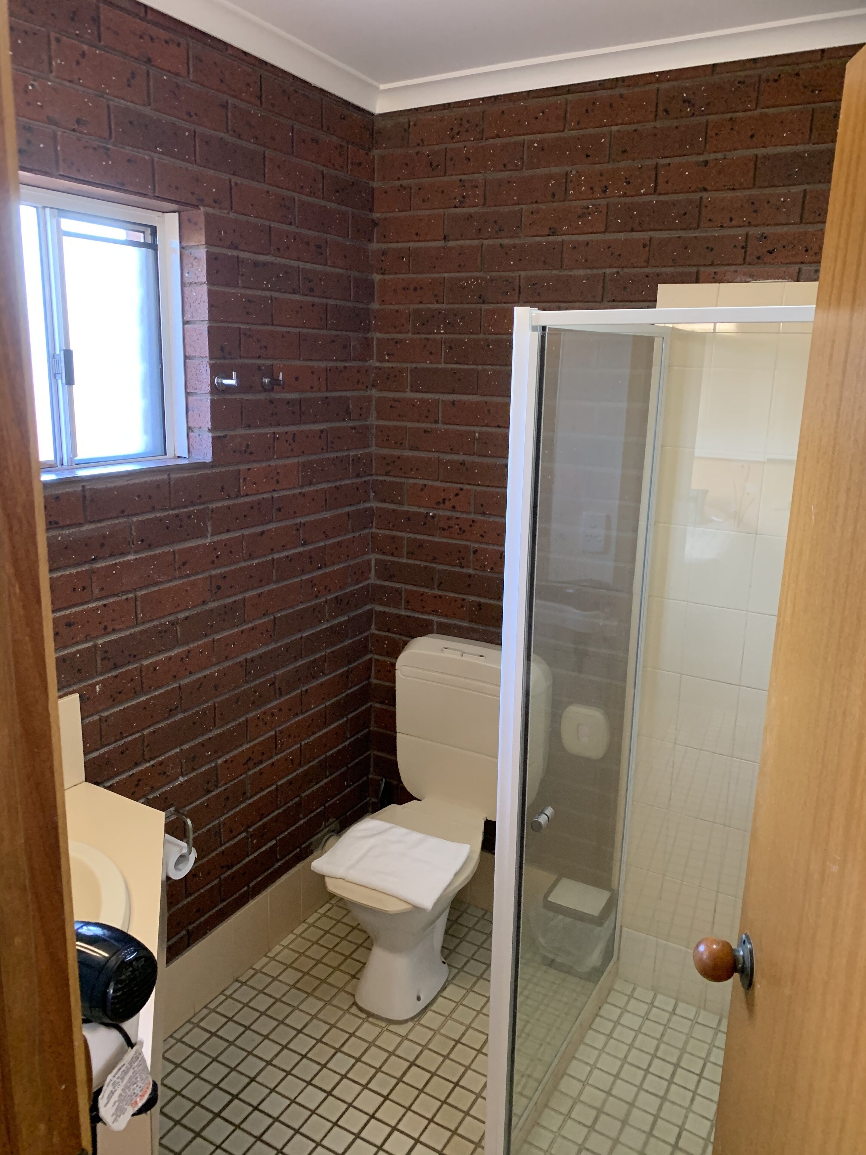 Ein Badezimmer mit Toilette, einem Fenster und einer Duschkabine.