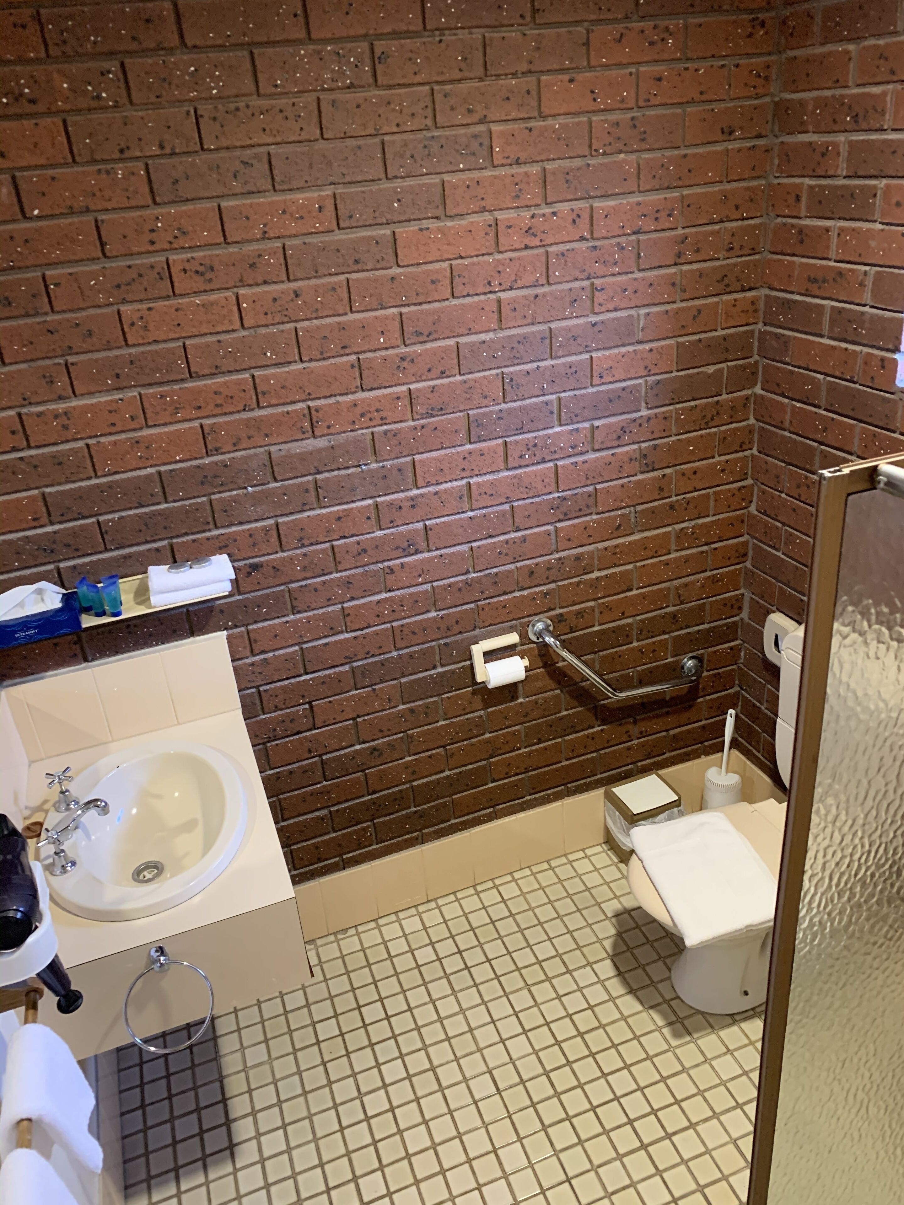 A bathroom with a sink, toilet, and a shower area.