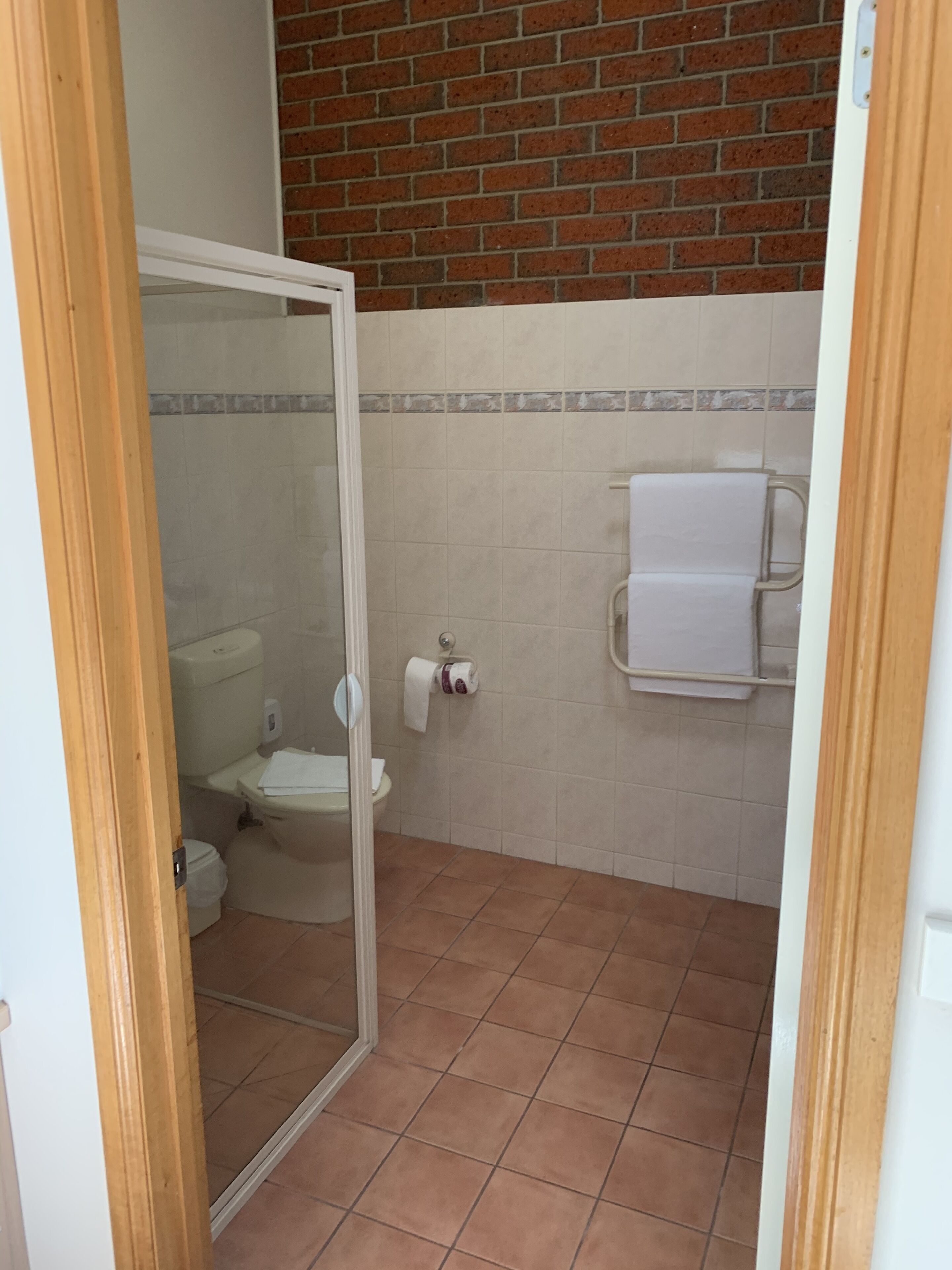 Un baño con inodoro, ducha y toallero.