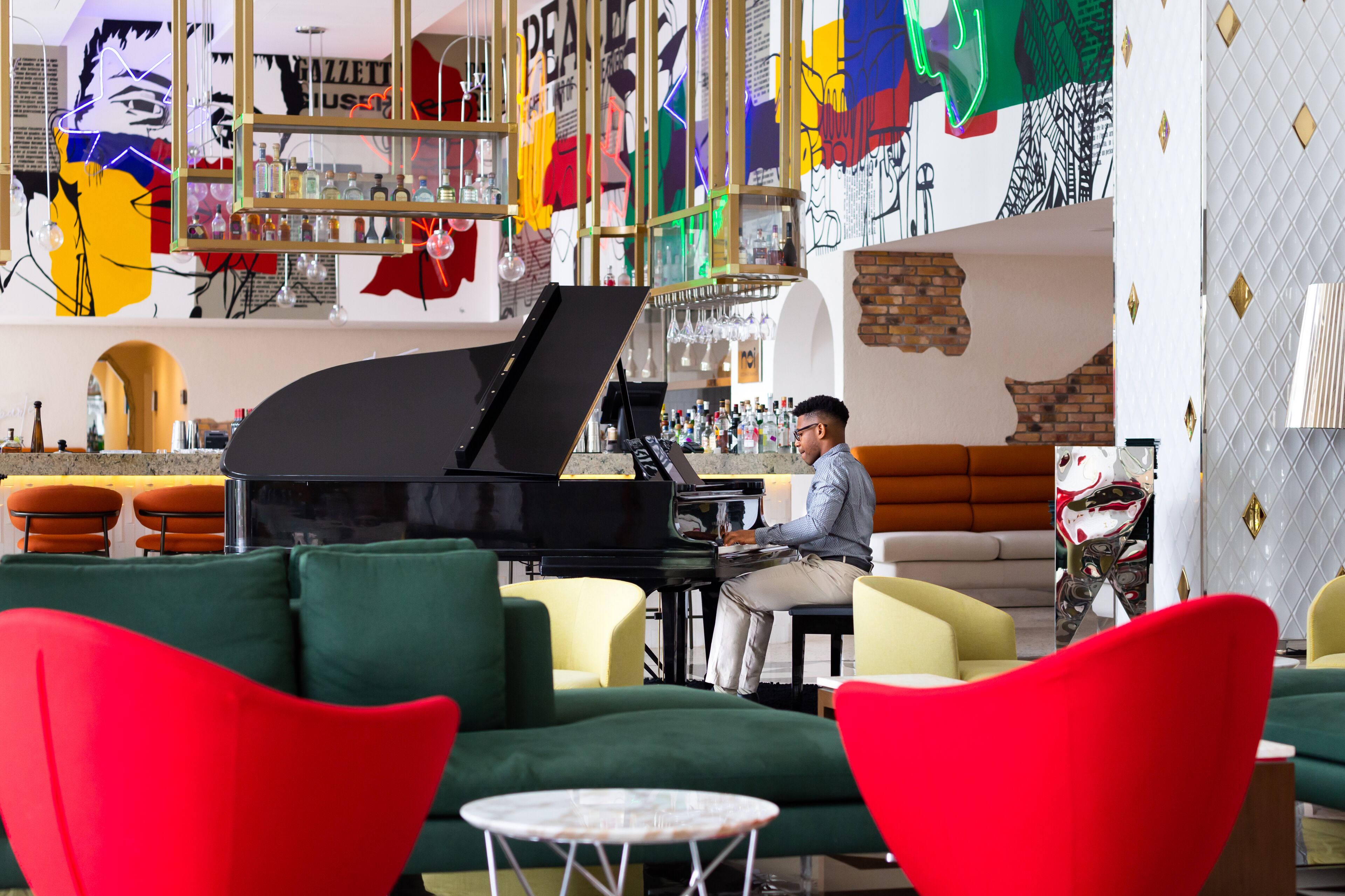 A bar area with a piano, green and red chairs, and a motorcycle.