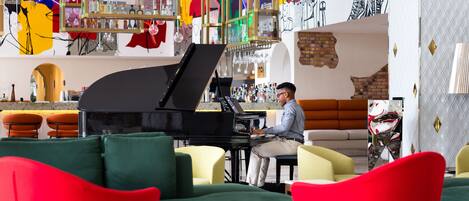 A bar area with a piano, green and red chairs, and a motorcycle.