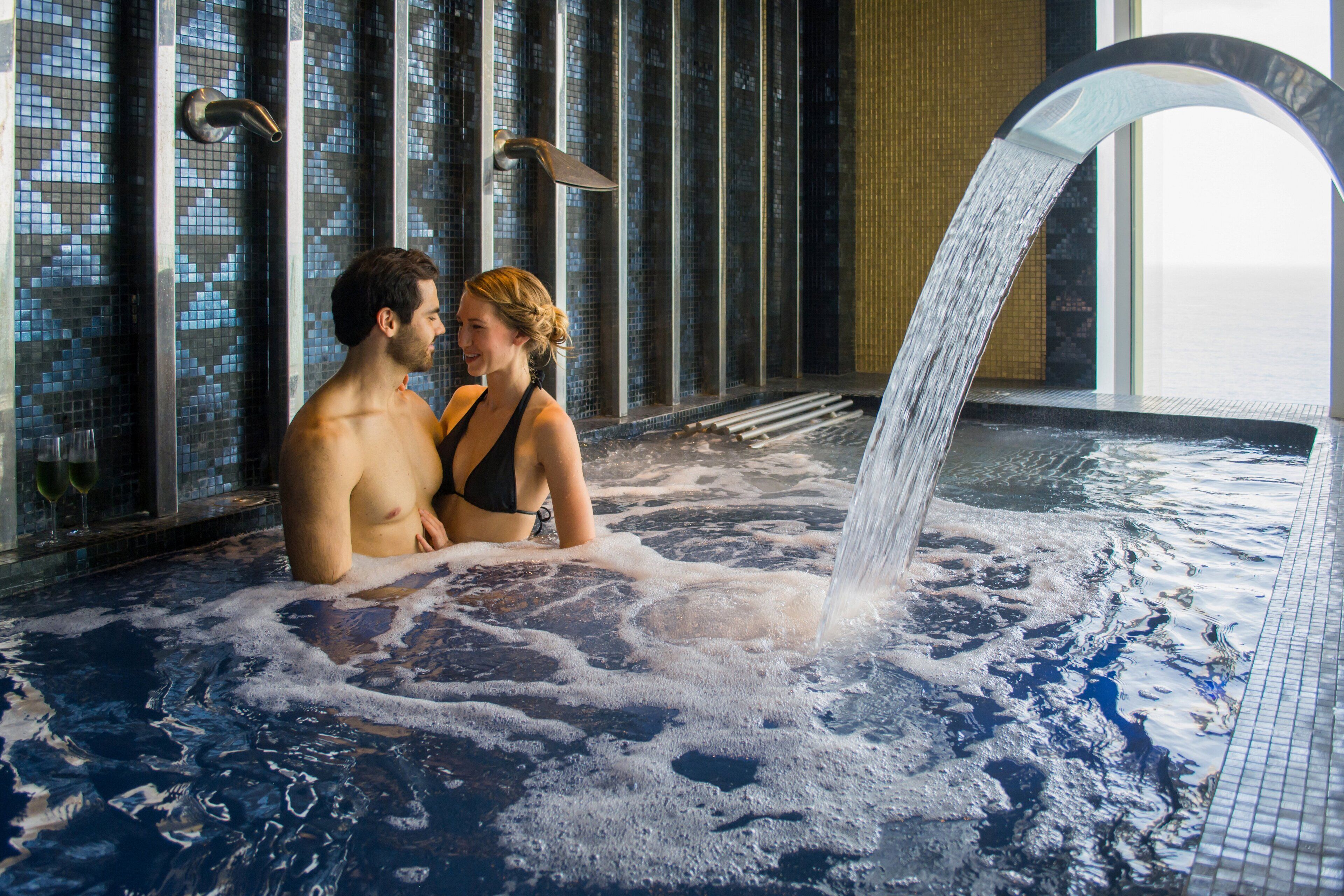 Um casal em uma banheira de hidromassagem com cachoeira.