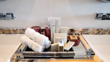 A bathroom vanity with a marble countertop, a towel rack, and various toiletries.