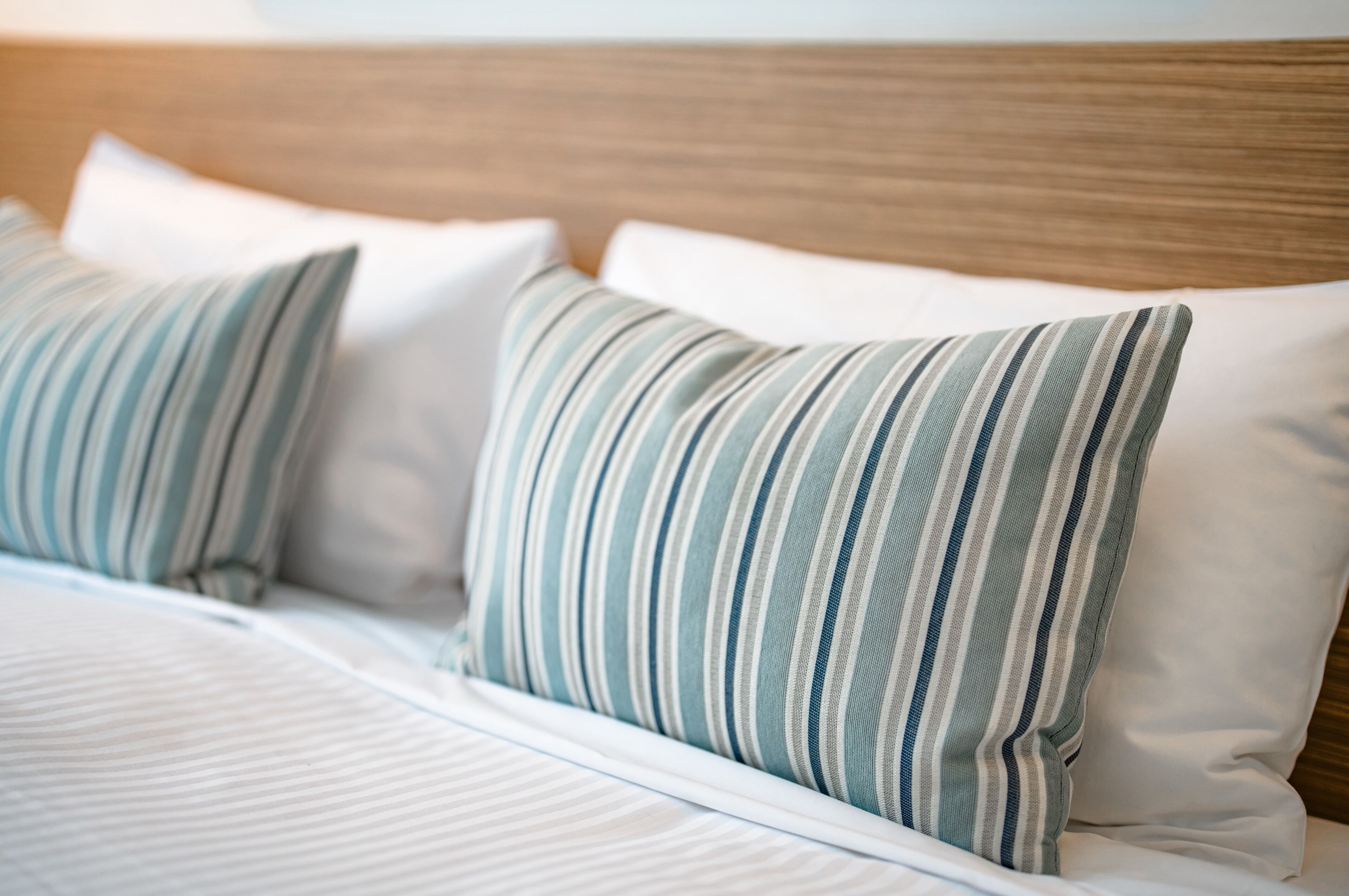 A bed with striped pillows and a wooden headboard.