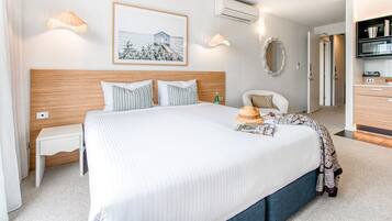 Habitación de hotel ordenada con una cama grande, mesitas de noche, un armario y un cuadro en la pared.