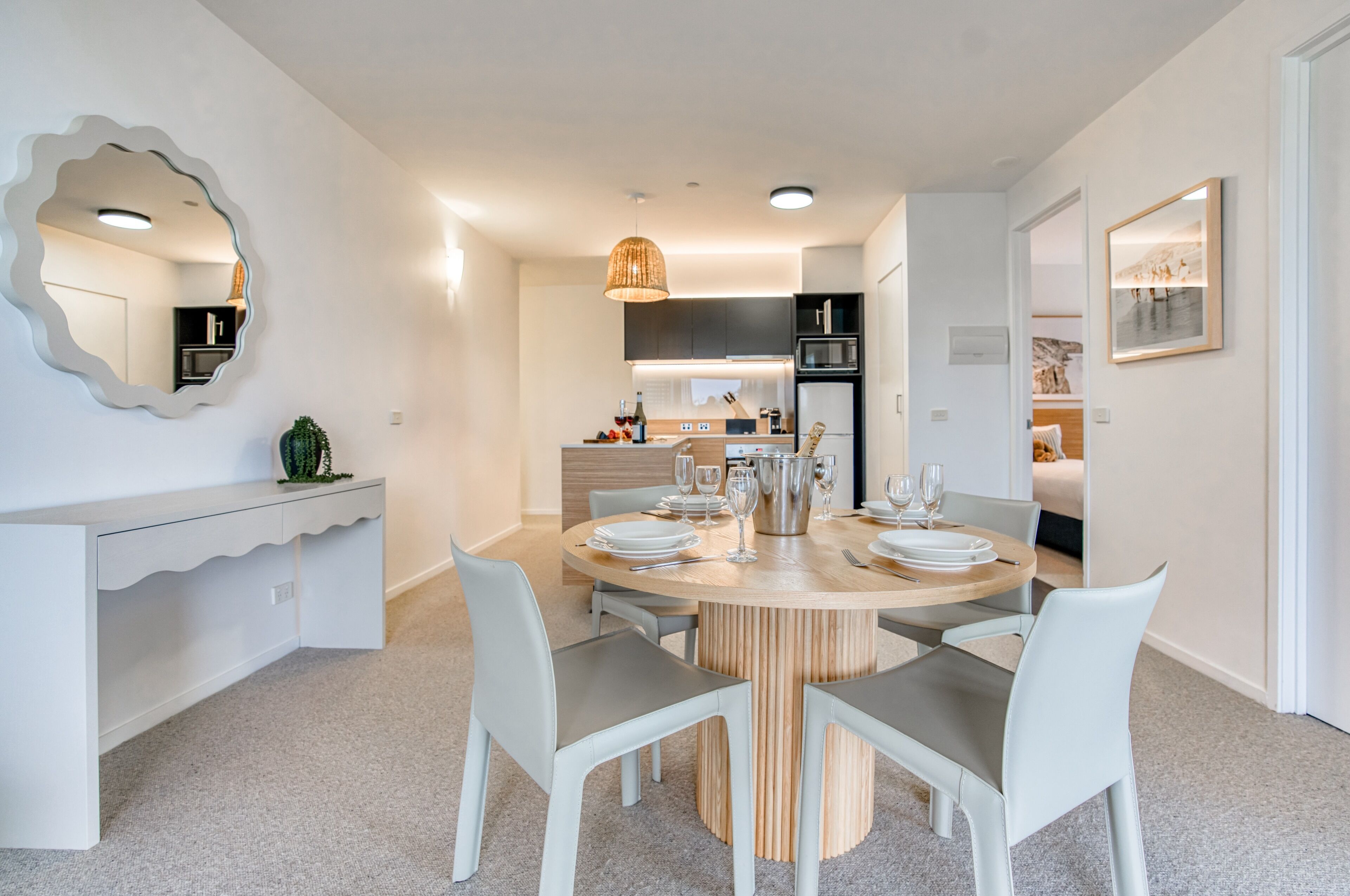 A modern dining area with a round table, white chairs, and a central light fixture.