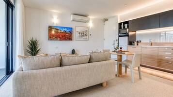 A modern living room with a sofa, a dining table, and a kitchen area.