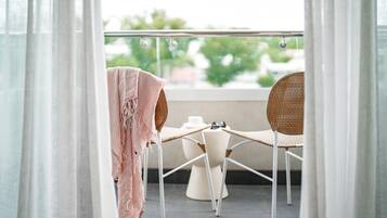 A balcony with two wicker chairs, a small table, and a white pedestal.