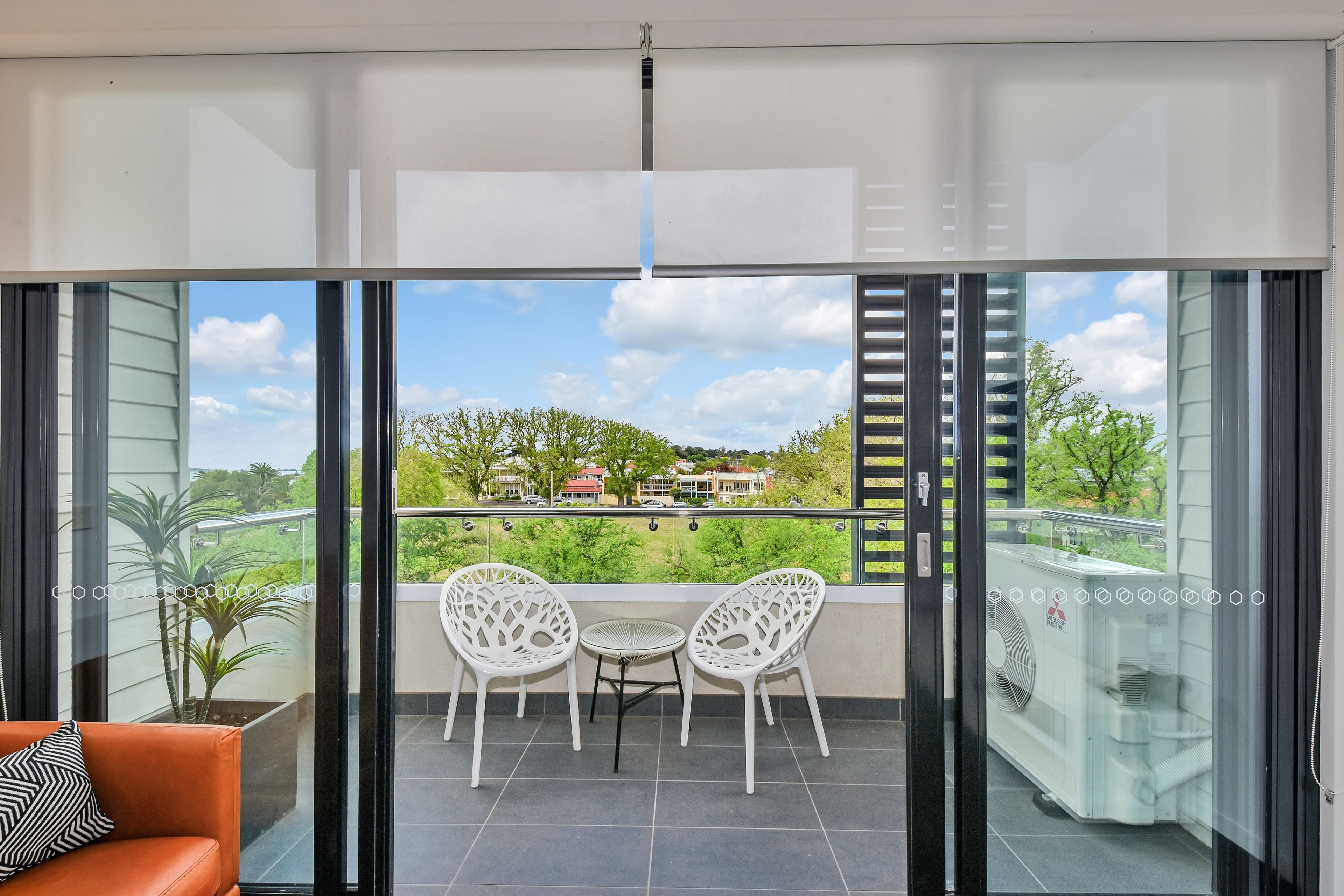 Un balcon avec une table et des chaises, un canapé et une vue sur un quartier résidentiel.