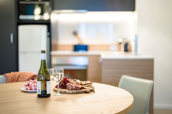 A dining table with a bottle of wine, a glass, and a plate of food.