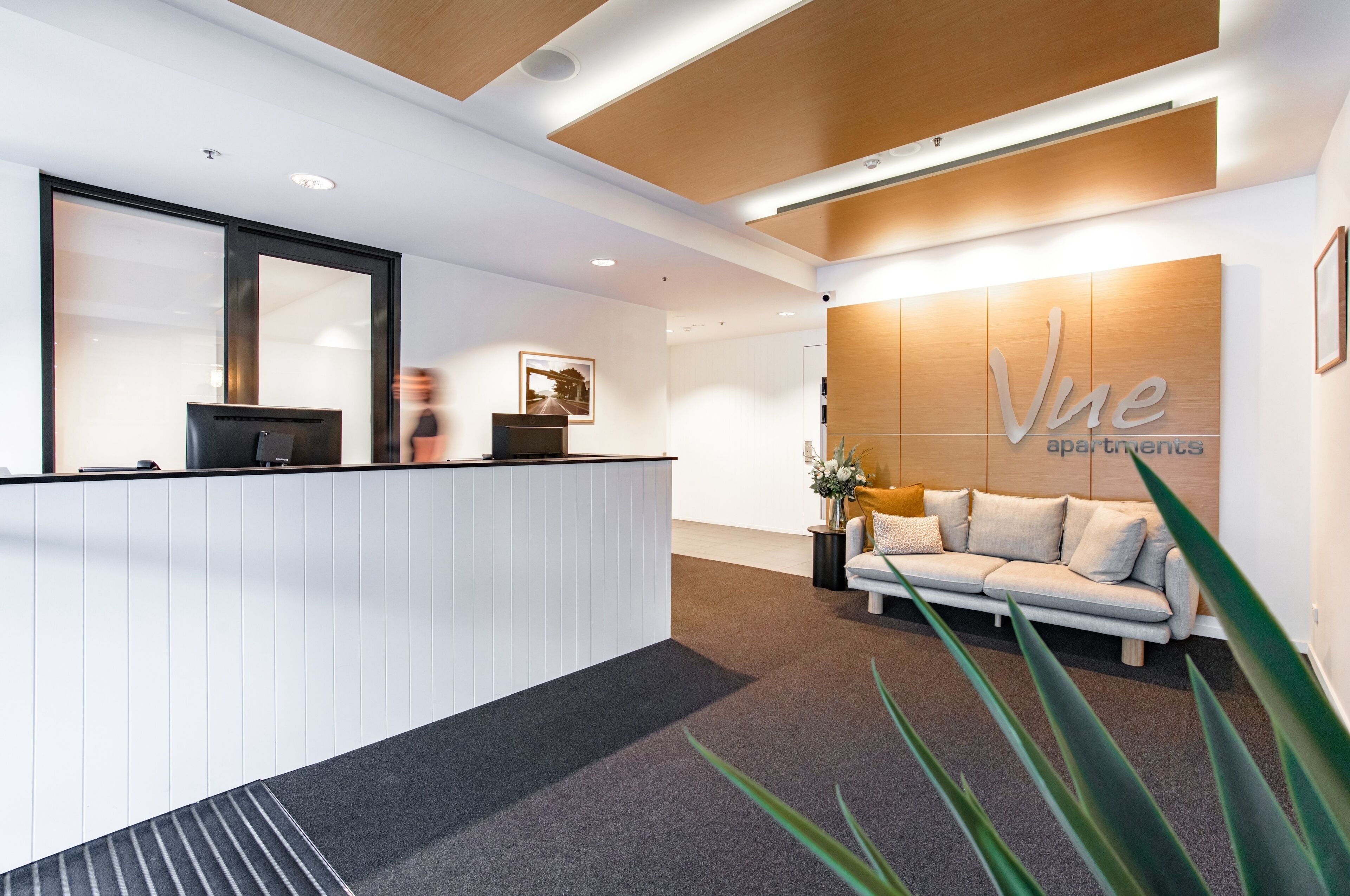 A reception area with a reception desk, a sofa, and a wall with the text "Vue apartments".