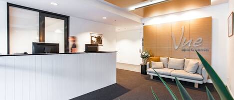 A reception area with a reception desk, a sofa, and a wall with the text "Vue apartments".