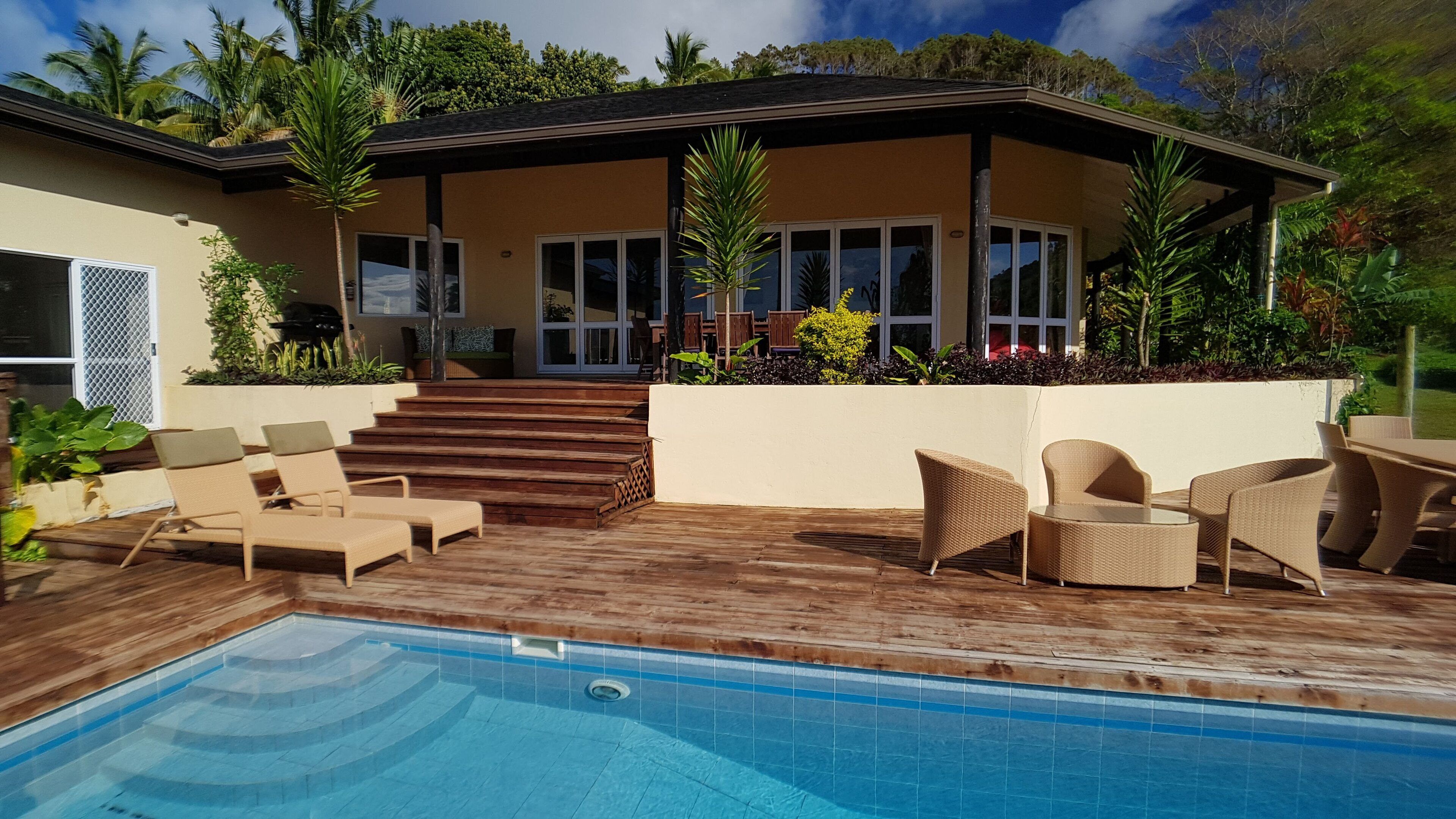 A modern house with a swimming pool, outdoor furniture, and a covered patio area.