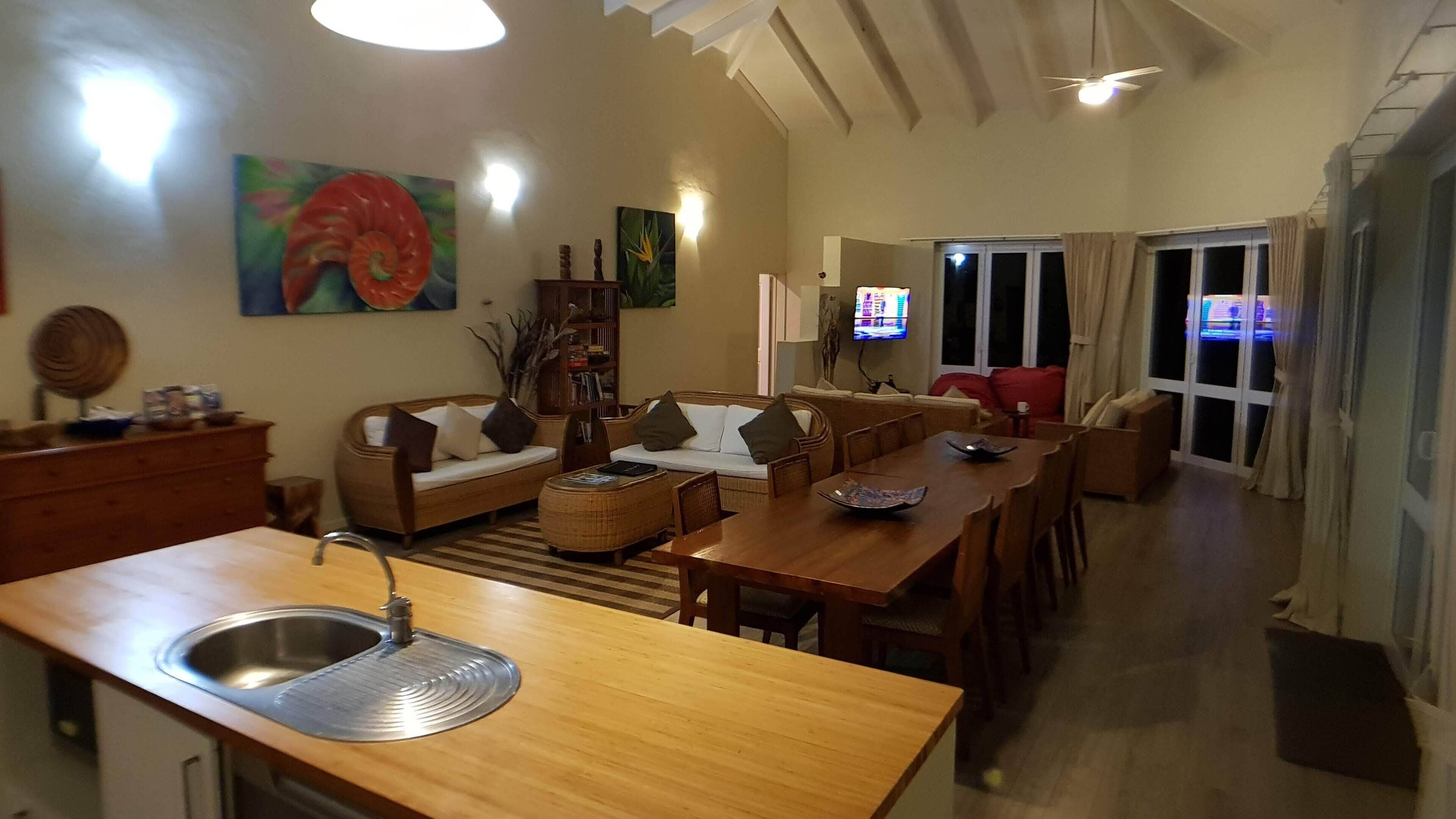Ampla sala de estar com cozinha, mesa de jantar e sofás.