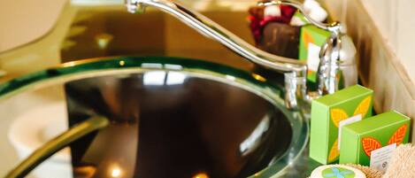 A bathroom sink with a green glass basin, a modern faucet, and a soap dish with a bar of soap.