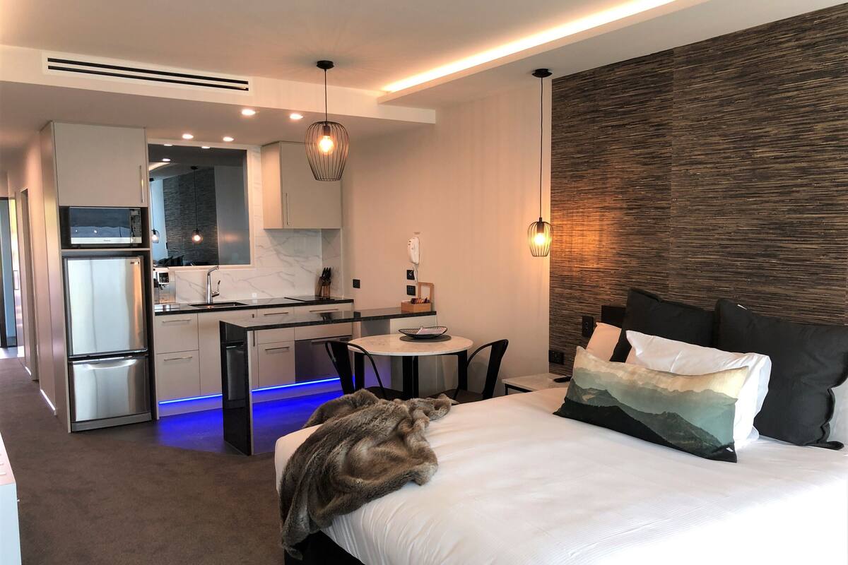 Een moderne hotelkamer met een bed, een zithoekje, een kitchenette en een badkamer.