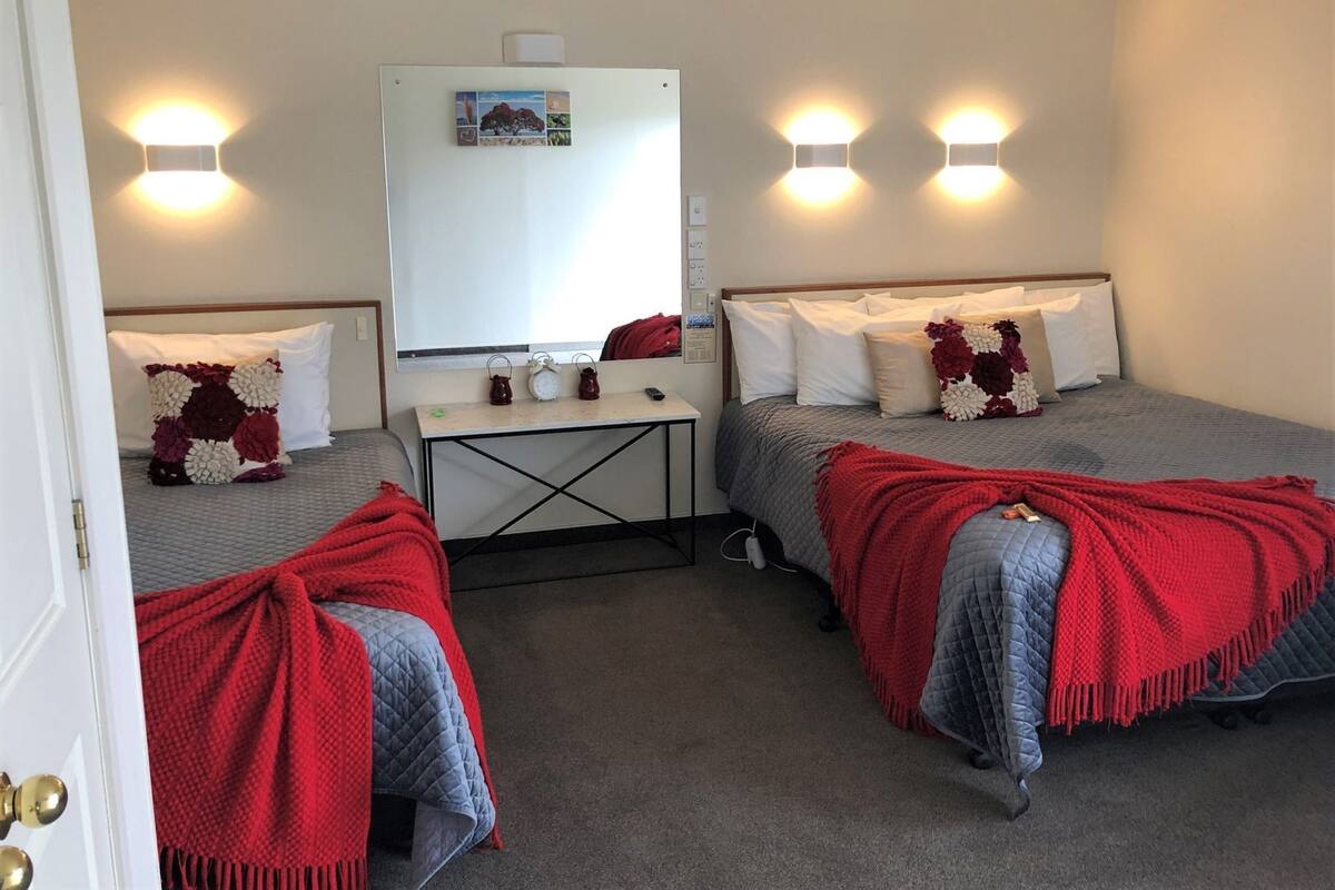Een hotelkamer met twee bedden, een bureau en een spiegel.