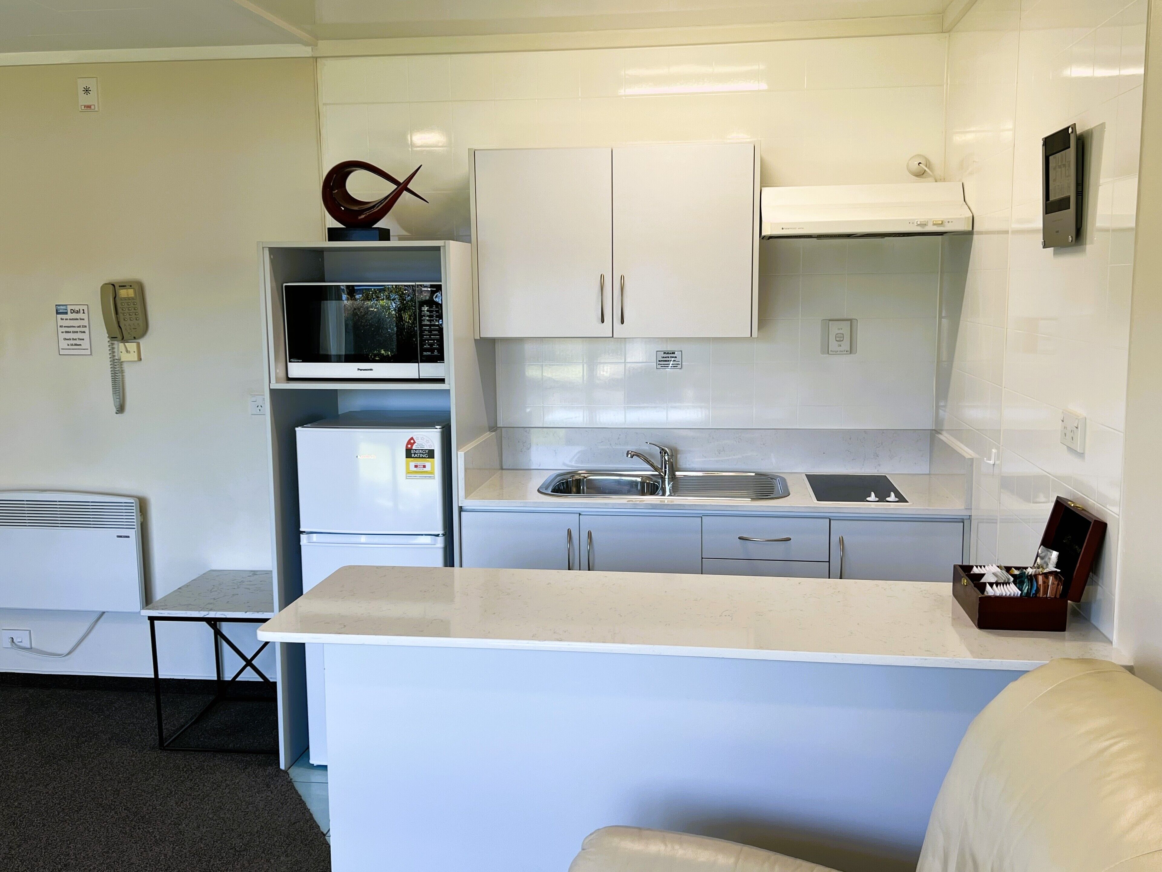 A compact kitchenette with a microwave, refrigerator, sink, and cabinets.