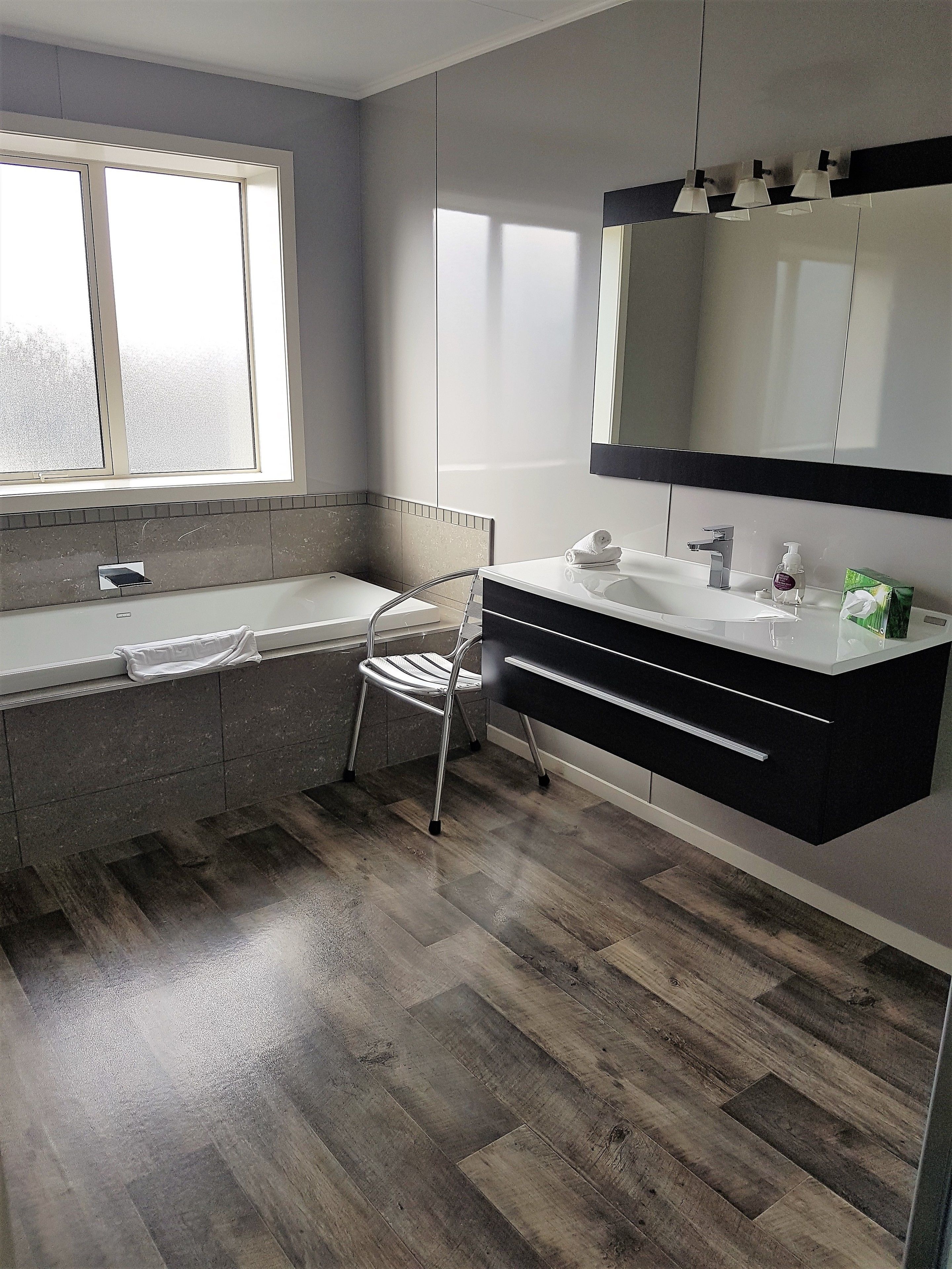 A modern bathroom with a bathtub, a vanity with a mirror, and a shower.