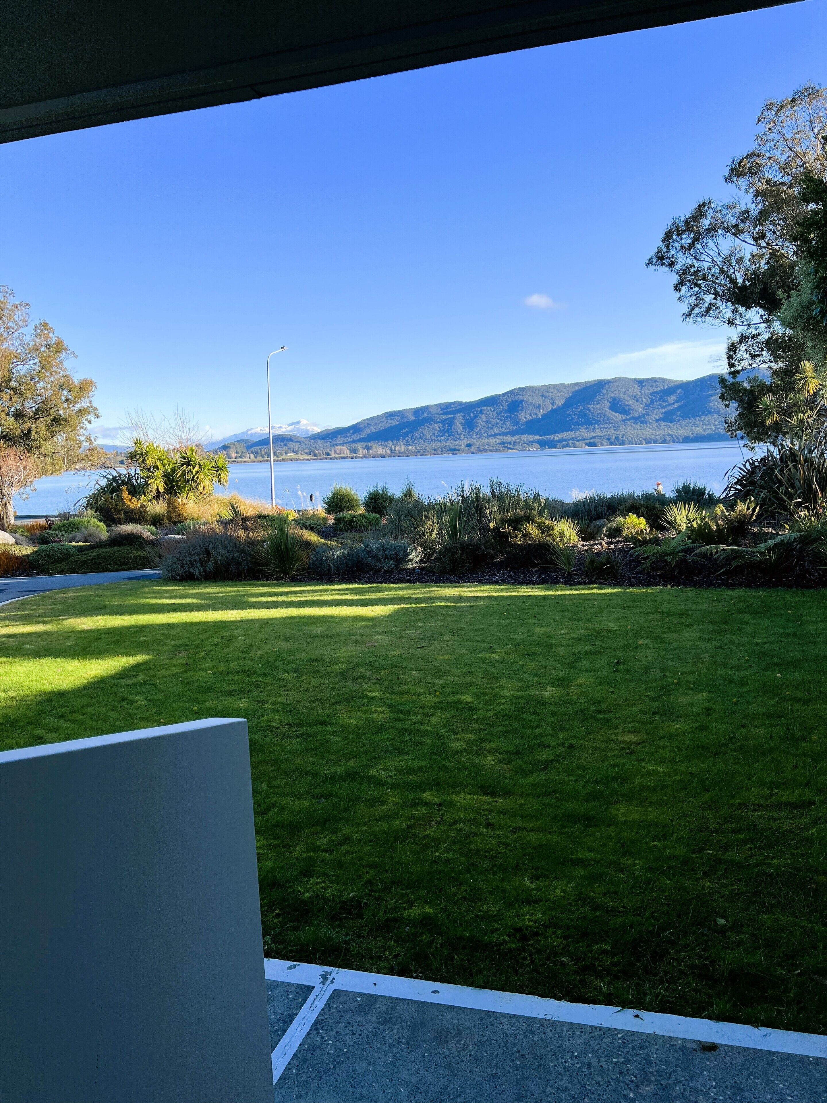 A view of a grassy area with a body of water and mountains in the background.