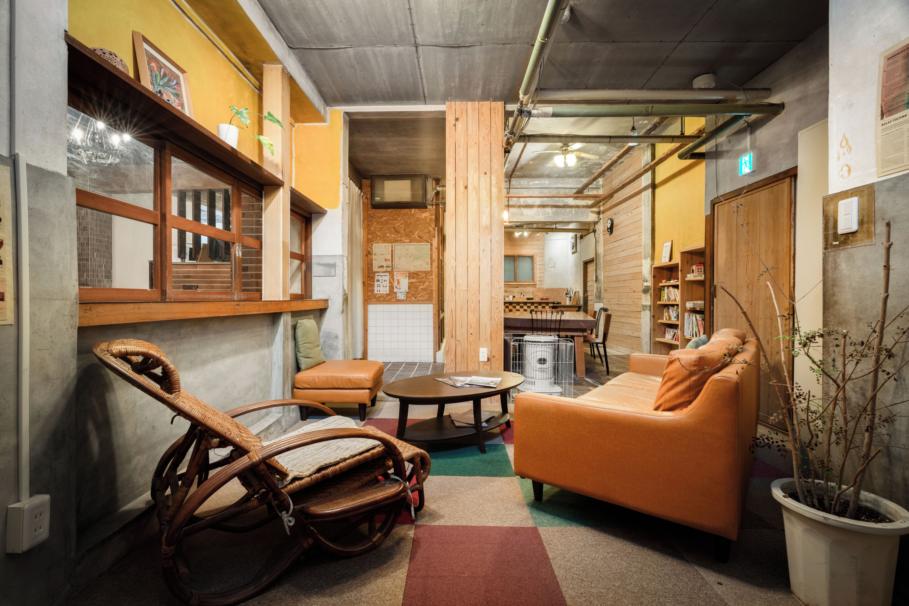 Un espacio habitable compacto con un sofá, una silla de mimbre, una mesita y una planta en maceta.