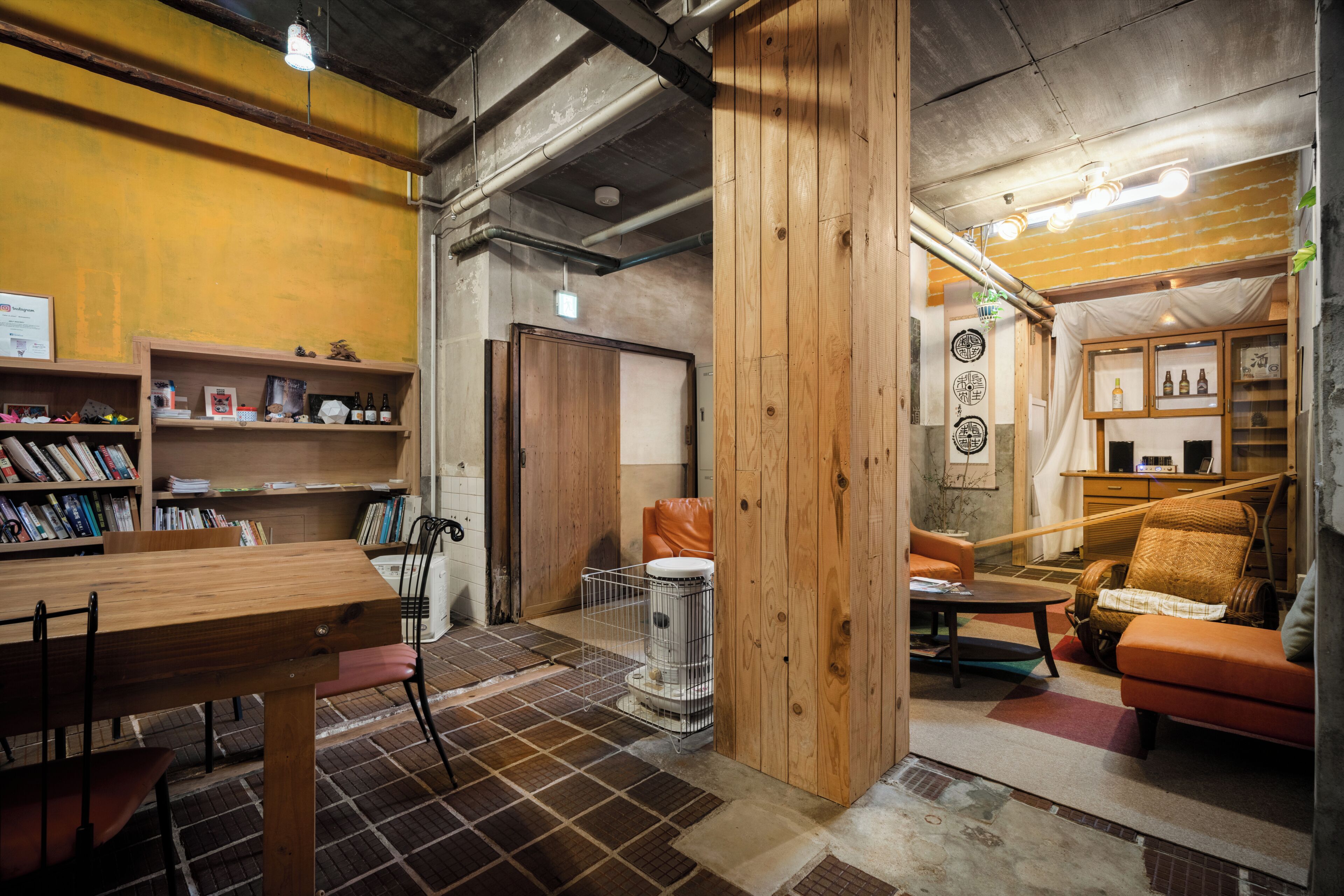 A room with a wooden table, chairs, a bookshelf, a trash bin, and a sofa.