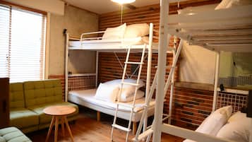 A bunk bed room with a green sofa and a small round table.