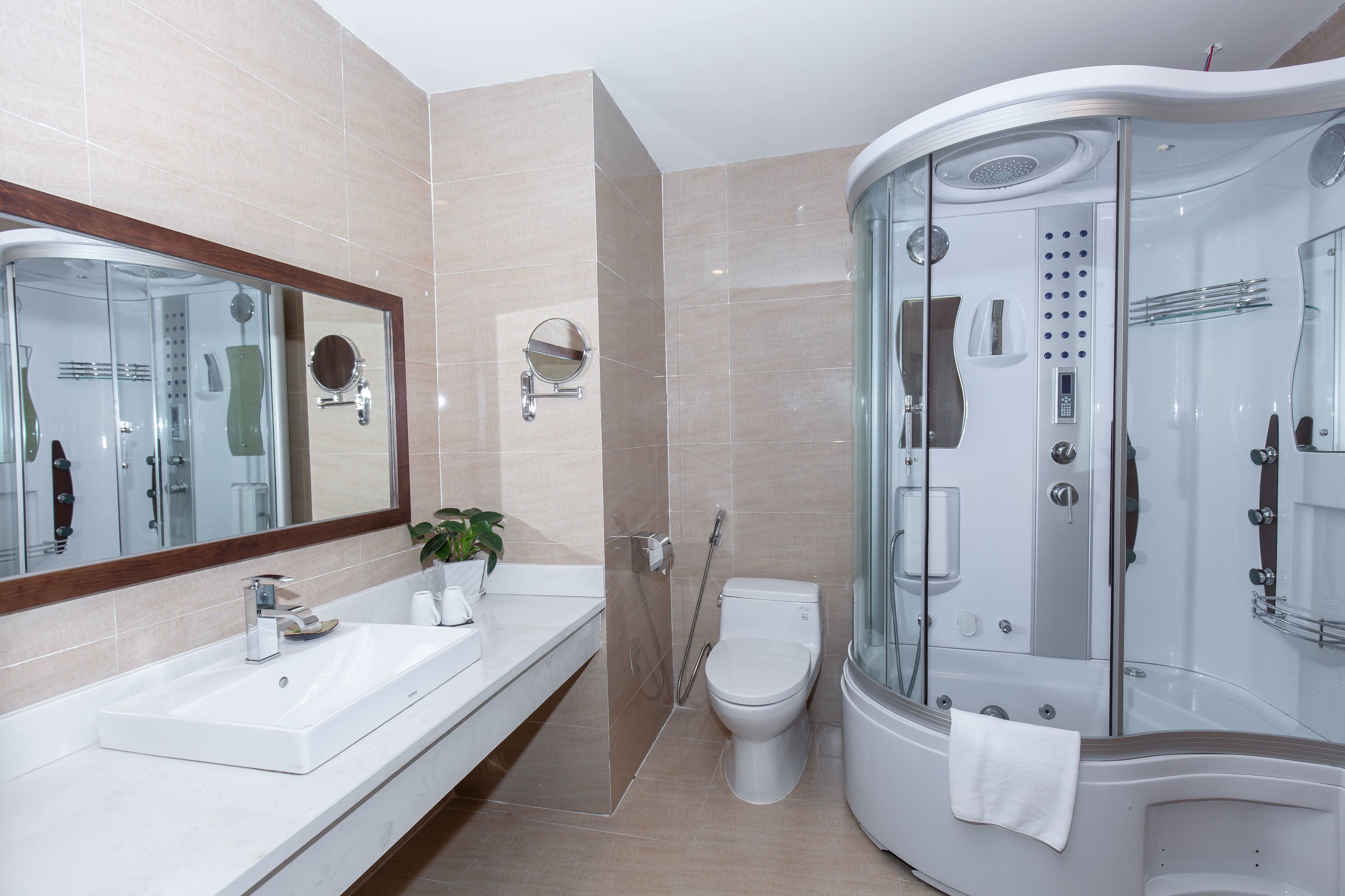 A modern bathroom with a glass-enclosed shower, a white sink, and a toilet.