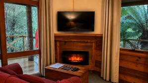 Una habitación acogedora con chimenea, un televisor colocado encima y un sofá rojo.