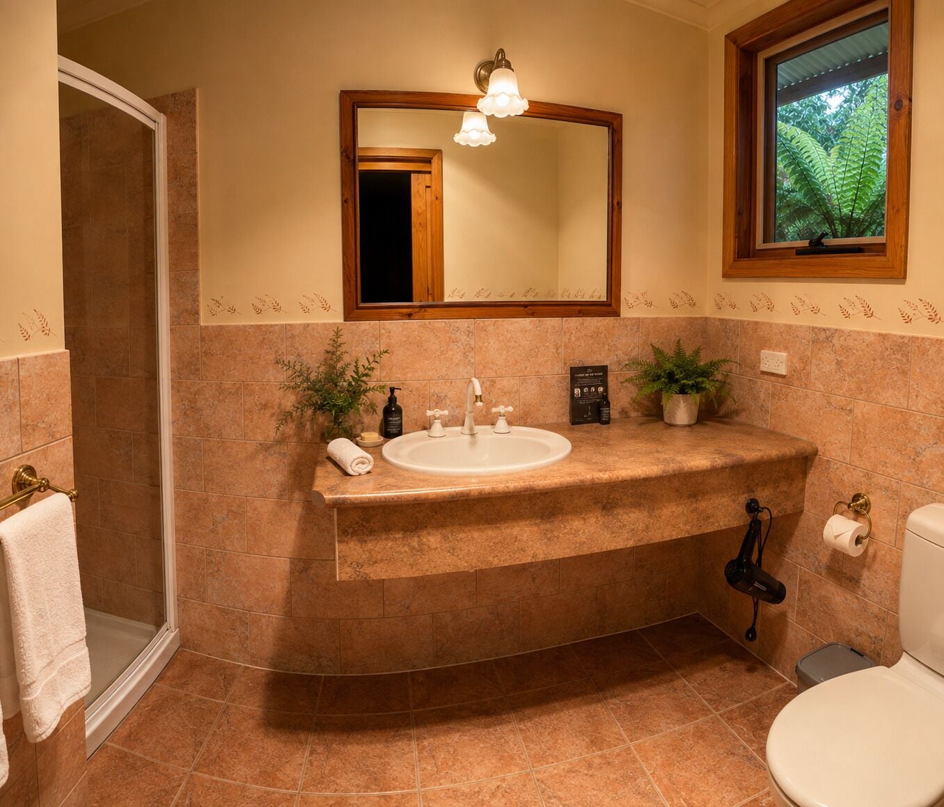 A bathroom with a curved sink, a mirror, a toilet, and a shower area.