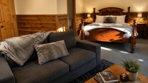 Une chambre à coucher avec un lit en bois, un canapé gris et une petite table sur laquelle se trouvent une plante et des livres.