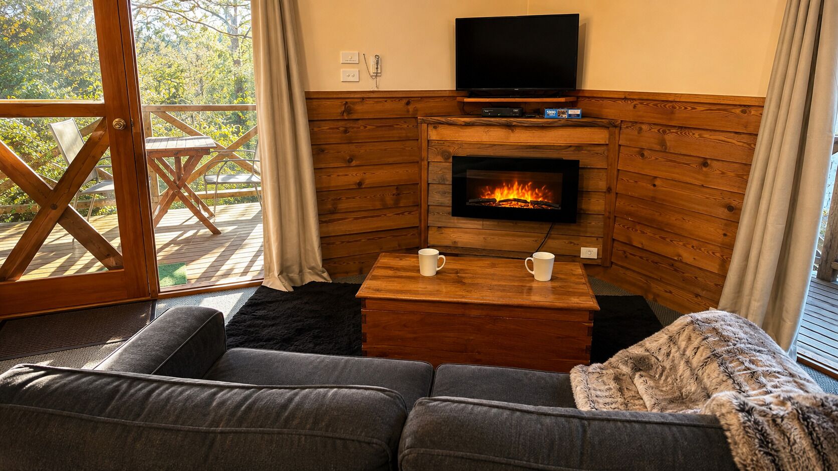A cozy living room with a fireplace, a sofa, and a television.