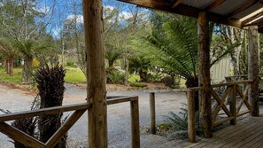 A wooden deck with a gravel path leading to a covered area, surrounded by various trees and plants. - Cradle Forest Inn (Moina)