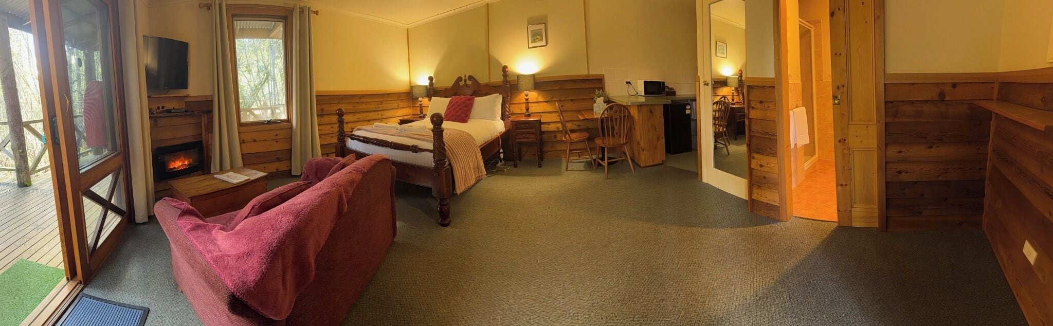 A cozy room with a bed, a TV, a fireplace, and a dining area.