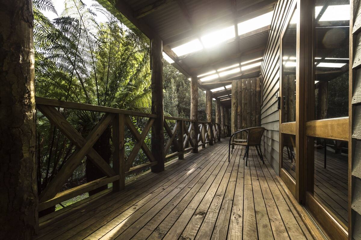 A wooden deck with a railing, overlooking a forested area.