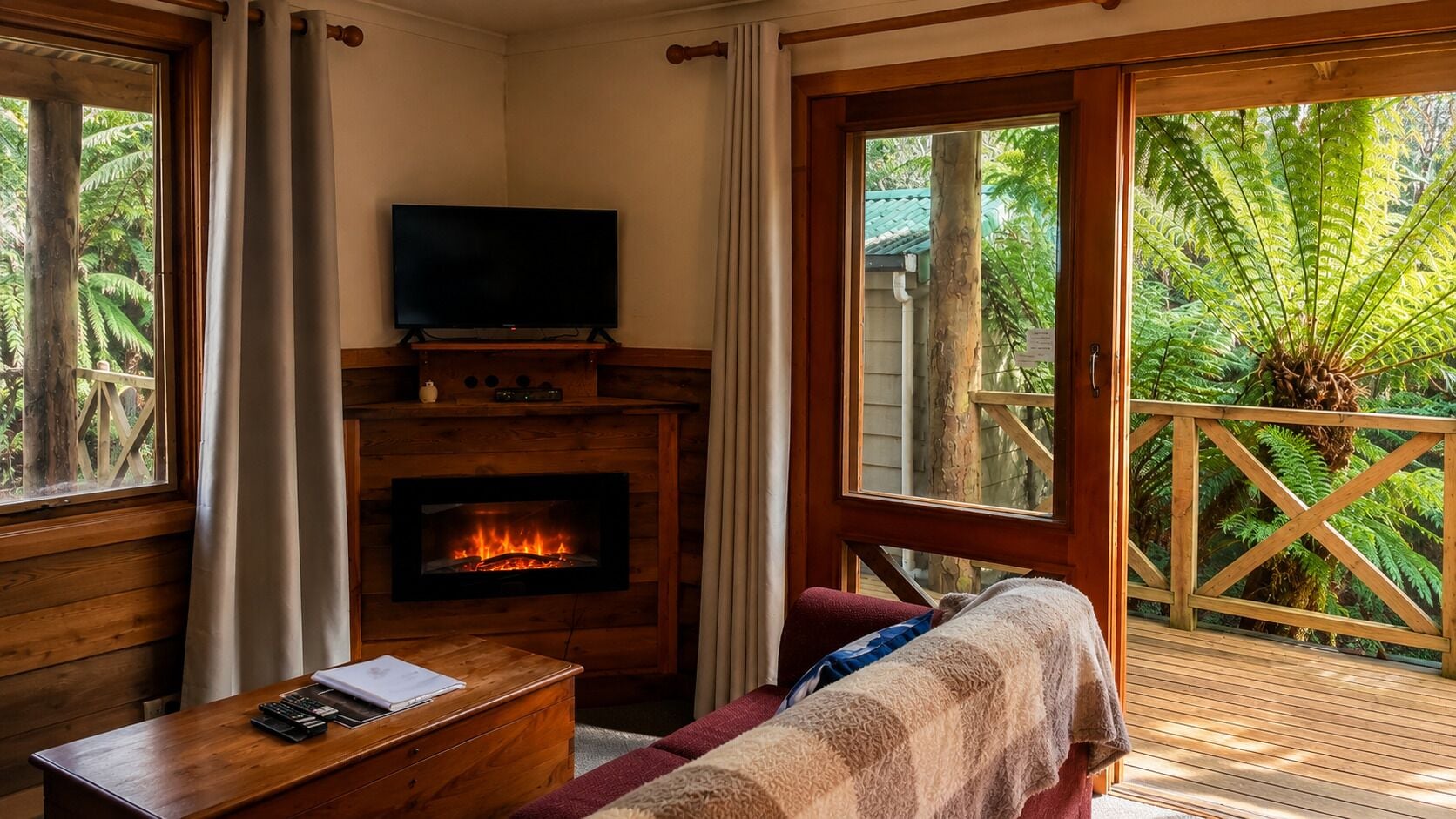 A cozy room with a fireplace, a television, and a view of lush greenery.