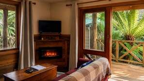 Una habitación acogedora con chimenea, televisión y vistas a exuberante vegetación.