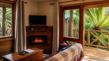 Una habitación acogedora con chimenea, televisión y vistas a exuberante vegetación.