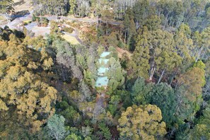 Vista aérea de una zona boscosa con un pequeño conjunto de edificios rodeados de árboles densos.