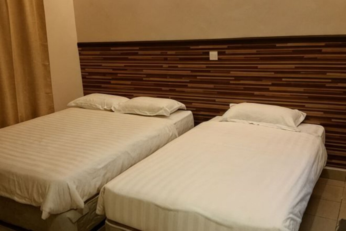 Two single beds with wooden headboards, a beige wall, and a curtain.