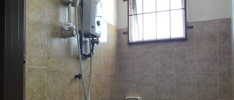 A bathroom with a sink, toilet, shower, and a window.