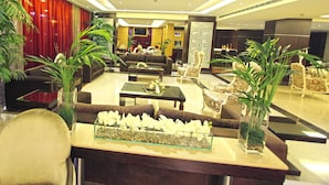 A spacious lobby with a sofa set, a coffee table, and a glass display case with flowers. - Elite Hotel & Spa (Beirut)