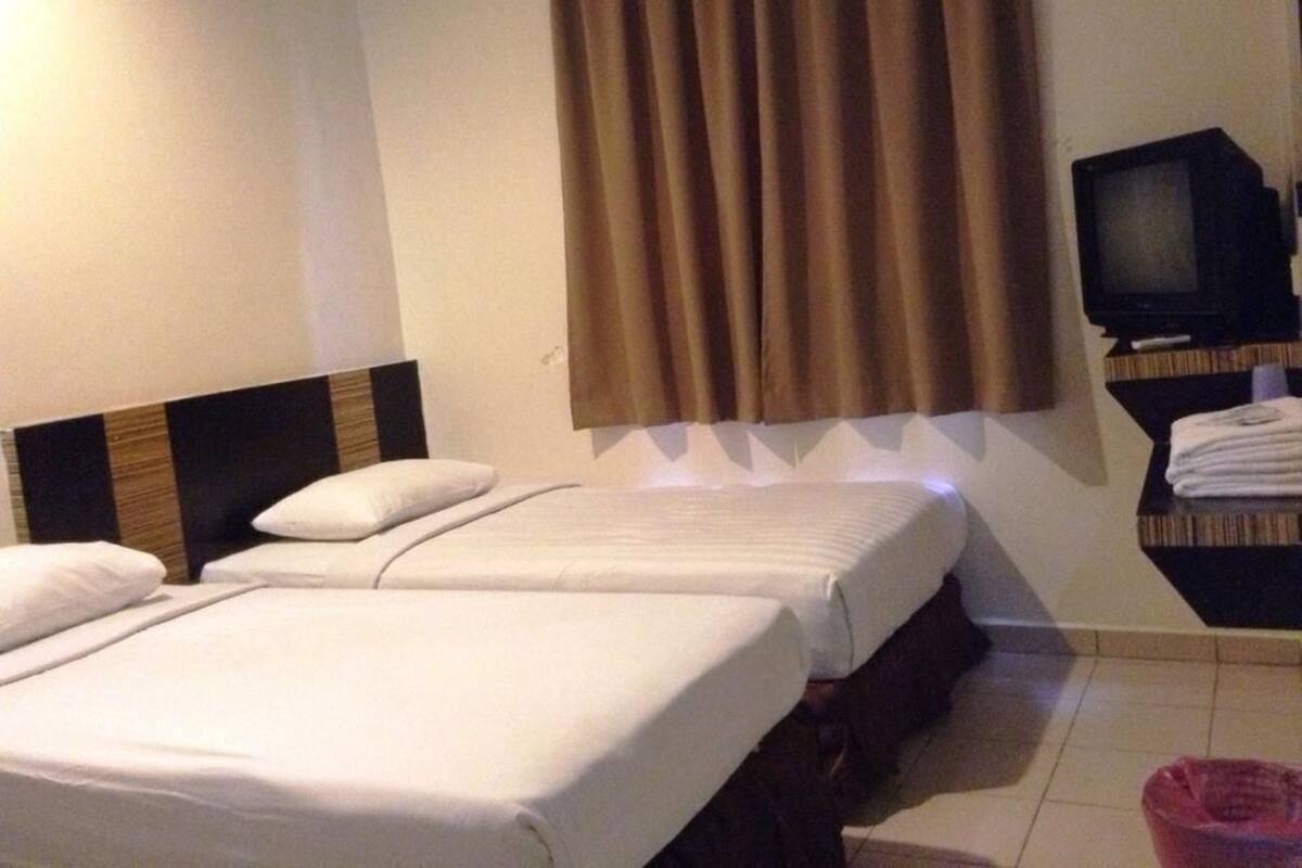 Ein Hotelzimmer mit zwei Betten, einem Fernseher und einem kleinen Tisch mit Handtüchern.