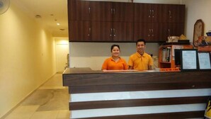 A reception desk with a wooden finish and a white base, flanked by dark wooden cabinets. - Hotel Traveller (Kota Kinabalu)