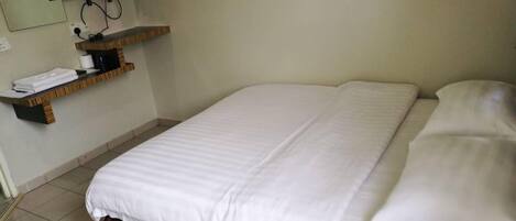 A hotel room with a bed, a TV mounted on the wall, and a shelf with towels.