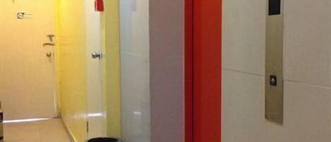 A hallway with a red elevator, a trash bin, and a sign that reads "KELUAR".