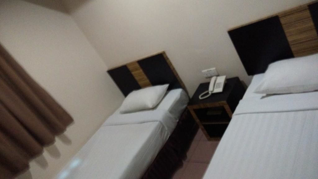 A hotel room with two single beds, a bedside table with a phone, and a nightstand.